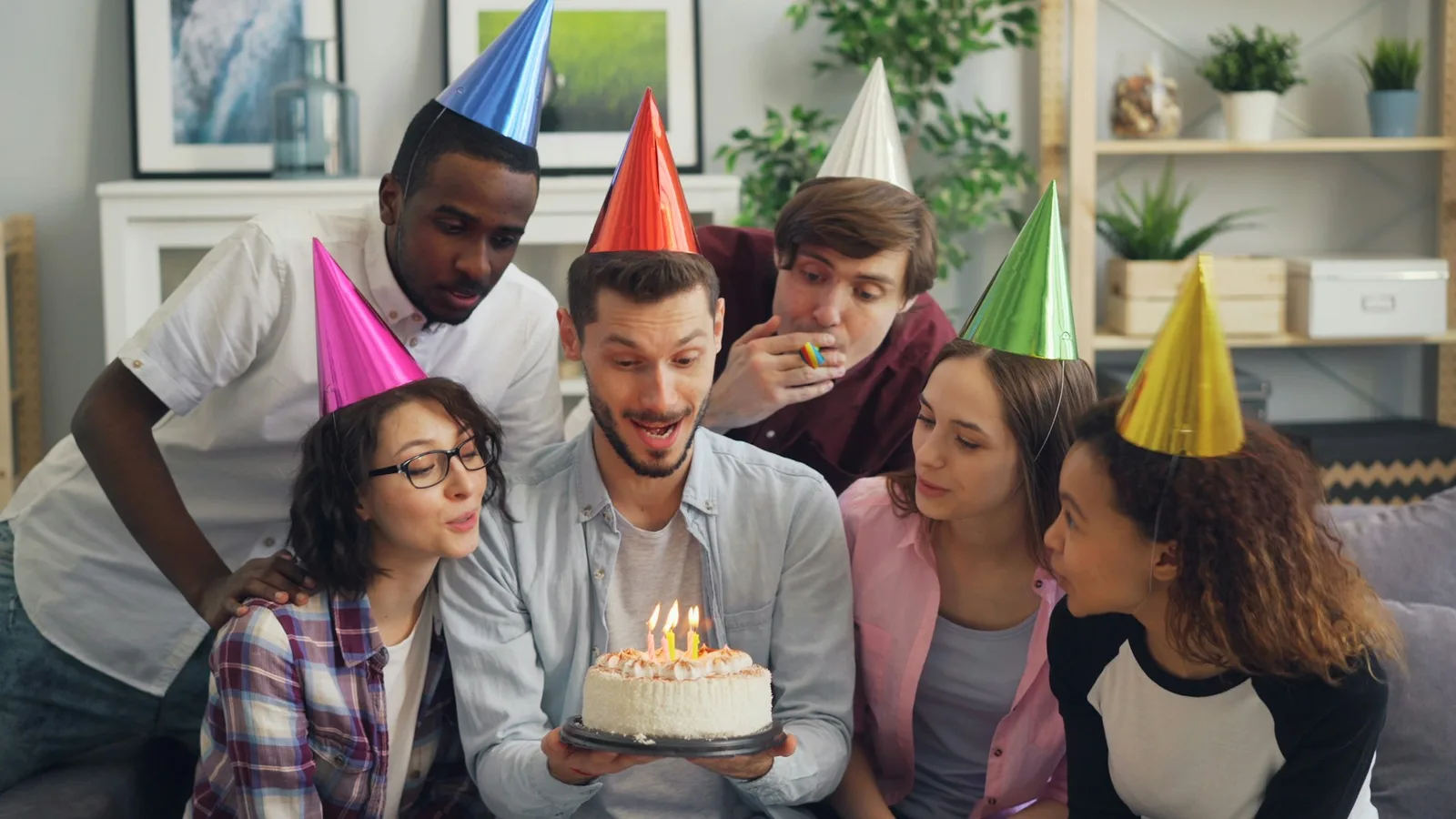 Friends in party hats gathered around a birthday cake